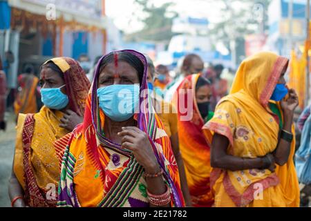 Kolkata, Westbengalen, Indien. Januar 2021. Das Tragen von Masken Frauen Pilger sind auf der Gangasagar Messe. Gangasagar Messe ist eine heilige jährliche Gemeinde von hinduistischen Pilgern. Diese findet auf der Insel Sagar statt, die am Zusammenfluss des Flusses Ganga und der Bucht von Bengalen liegt. Am Tag des "Sakar Sankranti" (14. Januar) nehmen Pilger an diesem Zusammenfluss ein heiliges Bad. Aufgrund der anhaltenden Pandemie-Situation ist das ganze unter starken COVID19-Protokollen eingeschränkt. In diesem Jahr sind die Hauptziele der Regierung regelmäßige Gesundheits-Check-up, Sanitierung des Ortes, Vermeidung von Menschenmengen usw. (Bild: © Santa Stockfoto