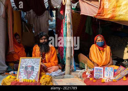 Kolkata, Westbengalen, Indien. Januar 2021. Mönche sitzen in den kleinen Hütten, die für sie auf dem Messegelände gemacht wurden. Gangasagar Messe ist eine heilige jährliche Gemeinde von hinduistischen Pilgern. Diese findet auf der Insel Sagar statt, die am Zusammenfluss des Flusses Ganga und der Bucht von Bengalen liegt. Am Tag des "Sakar Sankranti" (14. Januar) nehmen Pilger an diesem Zusammenfluss ein heiliges Bad. Aufgrund der anhaltenden Pandemie-Situation ist das ganze unter starken COVID19-Protokollen eingeschränkt. In diesem Jahr sind die Hauptziele der Regierung regelmäßige Gesundheits-Check-up, Sanitierung des Ortes, Vermeidung von Menschenmengen usw. (Credi Stockfoto