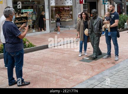 Oviedo, Asturien, Spanien: Touristen posieren mit Bronzestatue von Woody Allen, entworfen vom spanischen Bildhauer Vincente Menendez Santarua auf einem Gehweg Stockfoto