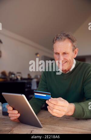 Senior Man Zu Hause Kauf Von Produkten Oder Dienstleistungen Online Mit Digitales Tablet Und Kreditkarte Stockfoto