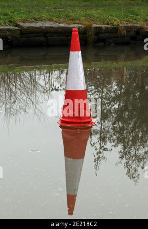 Kegel auf dem Eis, nach einem Zauber eiskalten Wetters war das Wasser des Kanals zugefroren und jemand hat einen Verkehrskegel auf dem Eis positioniert. Stockfoto