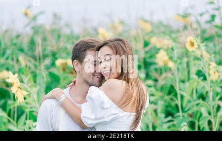 Schöne wunderschöne Frau und stilvolle gut aussehende männliche, rustikale Paar in einem Sonnenblumenfeld küssen Stockfoto