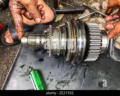 Die Hand des Technikers hält das Zahnrad des Fahrzeugs, das aus dem Motor entfernt wurde, um das Zahnrad auszutauschen. Stockfoto