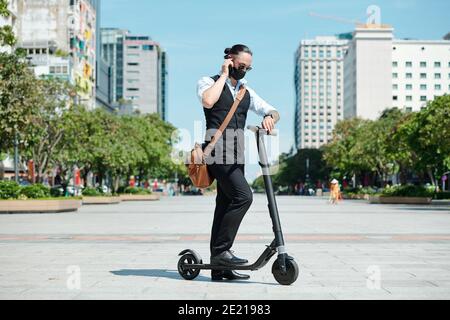 Stilvolle Unternehmer auf Elektroroller Stockfoto