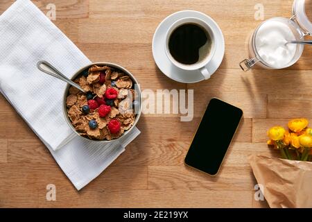Overhead Flat Lay Des Mobiltelefons Auf Tisch Gelegt Für Frühstück Mit Cerealien Und Kaffee Stockfoto