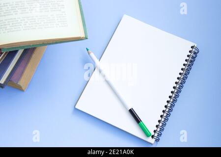 Stapel von bunten alten Hardback-Bücher mit offenem Notizbuch und Bleistift. Zurück zur Schule. Hardcover Bücher auf violettem Hintergrund. Draufsicht Stockfoto