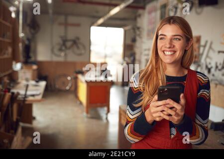 Weibliche Geschäftsinhaberin Im Workshop Mit Mobiltelefon Stockfoto