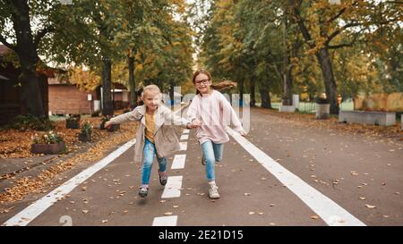 Zwei niedliche kleine Mädchen, die Spaß zusammen haben und Hände halten Beim Laufen im Park Stockfoto