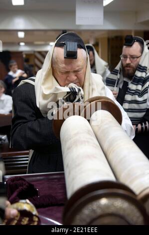 Ein älterer orthodoxer jüdischer Mann hebt die Tora leicht an, nachdem er an Wochentagen morgens zum Lesen gerufen wurde. In Crown Heights, Brooklyn. Stockfoto