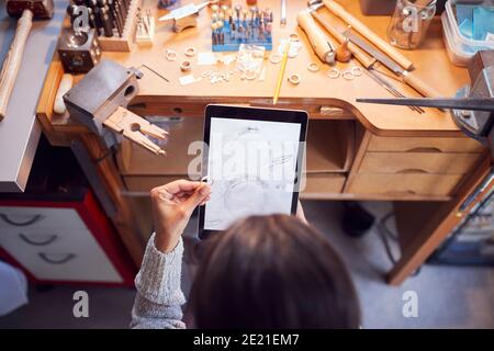 Overhead-Ansicht Der Weiblichen Juwelierin Vergleich Ring Mit Gezeichneten Design Auf Einem Digitalen Tablet In Studio Stockfoto