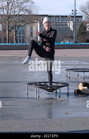 Eine Frau in einer Rebounding-Klasse, die kräftige Bewegungen beim Springen auf einem kleinen Trampolin kombiniert. In Flushing Meadows Corona Park in Queens, NYC. Stockfoto