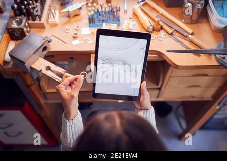 Overhead-Ansicht Der Weiblichen Juwelierin Vergleich Ring Mit Gezeichneten Design Auf Einem Digitalen Tablet In Studio Stockfoto