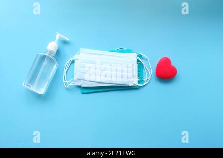 Chirurgische Masken, Hand-Desinfektionsmittel mit Herzform auf farbigem Hintergrund Stockfoto