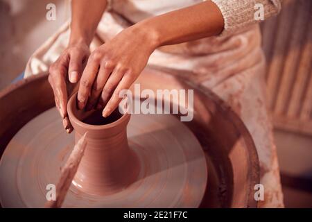 Nahaufnahme Von Weibliche Potter Shaping Clay Für Pot On Töpferscheibe Im Keramik-Studio Stockfoto