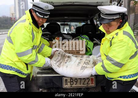 (210111) -- PANZHOU, 11. Januar 2021 (Xinhua) -- Verkehrspolizisten bewegen einen Sack Industriesalz, ein Eisschmelzmittel, auf der Donghu-Brücke in der Stadt Panzhou im Südwesten Chinas, Provinz Guizhou, 11. Januar 2021. Die jüngste starke Kältewelle hat in Panzhou und vielen anderen Orten in Guizhou zu einer Staubildung geführt. Rund 400 Verkehrspolizisten in Panzhou arbeiten nun rund um die Uhr daran, die Straßenflächen der Eisverkleidungen in der Stadt zu entfernen. Das fluoreszierende Grün auf ihren Jacken scheint die wärmste Farbe in einem frostigen Winter zu sein. (Xinhua/Ou Dongqu) Stockfoto