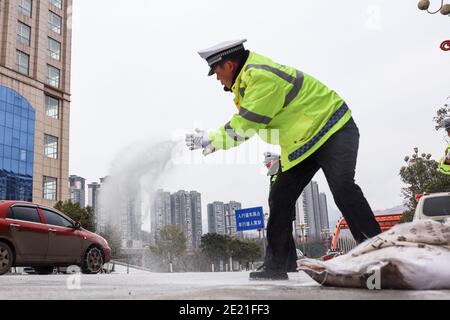 (210111) -- PANZHOU, 11. Januar 2021 (Xinhua) -- Verkehrspolizisten verbreiten industrielles Salz, ein Eisschmelzmittel, auf der Donghu-Brücke in der Stadt Panzhou im Südwesten Chinas, Provinz Guizhou, 11. Januar 2021. Die jüngste starke Kältewelle hat in Panzhou und vielen anderen Orten in Guizhou zu einer Staubildung geführt. Rund 400 Verkehrspolizisten in Panzhou arbeiten nun rund um die Uhr daran, die Straßenflächen der Eisverkleidungen in der Stadt zu entfernen. Das fluoreszierende Grün auf ihren Jacken scheint die wärmste Farbe in einem frostigen Winter zu sein. (Xinhua/Ou Dongqu) Stockfoto