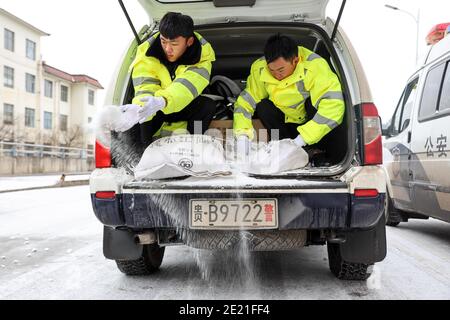 (210111) -- PANZHOU, 11. Januar 2021 (Xinhua) -- Verkehrspolizisten verbreiten industrielles Salz, ein Eisschmelzmittel, auf der Elangpu-Brücke in der Stadt Panzhou im Südwesten Chinas, Provinz Guizhou, 11. Januar 2021. Die jüngste starke Kältewelle hat in Panzhou und vielen anderen Orten in Guizhou zu einer Staubildung geführt. Rund 400 Verkehrspolizisten in Panzhou arbeiten nun rund um die Uhr daran, die Straßenflächen der Eisverkleidungen in der Stadt zu entfernen. Das fluoreszierende Grün auf ihren Jacken scheint die wärmste Farbe in einem frostigen Winter zu sein. (Xinhua/Ou Dongqu) Stockfoto