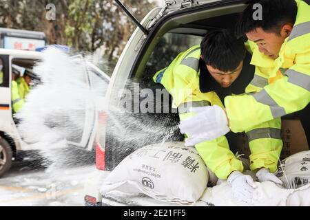 (210111) -- PANZHOU, 11. Januar 2021 (Xinhua) -- Verkehrspolizisten verbreiten industrielles Salz, ein Eisschmelzmittel, auf der Elangpu-Brücke in der Stadt Panzhou im Südwesten Chinas, Provinz Guizhou, 11. Januar 2021. Die jüngste starke Kältewelle hat in Panzhou und vielen anderen Orten in Guizhou zu einer Staubildung geführt. Rund 400 Verkehrspolizisten in Panzhou arbeiten nun rund um die Uhr daran, die Straßenflächen der Eisverkleidungen in der Stadt zu entfernen. Das fluoreszierende Grün auf ihren Jacken scheint die wärmste Farbe in einem frostigen Winter zu sein. (Xinhua/Ou Dongqu) Stockfoto