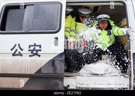 (210111) -- PANZHOU, 11. Januar 2021 (Xinhua) -- Verkehrspolizisten verbreiten industrielles Salz, ein Eisschmelzmittel, auf der Donghu-Brücke in der Stadt Panzhou im Südwesten Chinas, Provinz Guizhou, 11. Januar 2021. Die jüngste starke Kältewelle hat in Panzhou und vielen anderen Orten in Guizhou zu einer Staubildung geführt. Rund 400 Verkehrspolizisten in Panzhou arbeiten nun rund um die Uhr daran, die Straßenflächen der Eisverkleidungen in der Stadt zu entfernen. Das fluoreszierende Grün auf ihren Jacken scheint die wärmste Farbe in einem frostigen Winter zu sein. (Xinhua/Ou Dongqu) Stockfoto