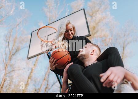 Low-Winkel-Ansicht von glücklichen jungen Paar mit Ball bleiben Auf dem Basketballplatz im Freien Stockfoto