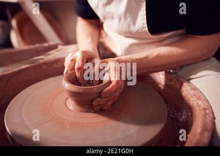 Nahaufnahme Von Weibliche Potter Shaping Clay Für Pot On Töpferscheibe Im Keramik-Studio Stockfoto