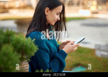 Seitenansicht Porträt von liebenswert junge Student Blick auf Smartphone Bildschirm im Freien Stockfoto
