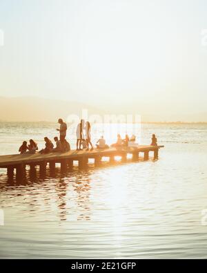 Dock im Meer mit Menschen beobachten den Sonnenuntergang Stockfoto