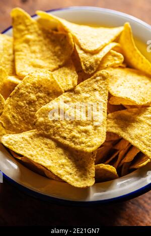 Gesalzene Tortilla-Chips. Gelbes Nachos Dreieck in Schale auf Holztisch. Stockfoto