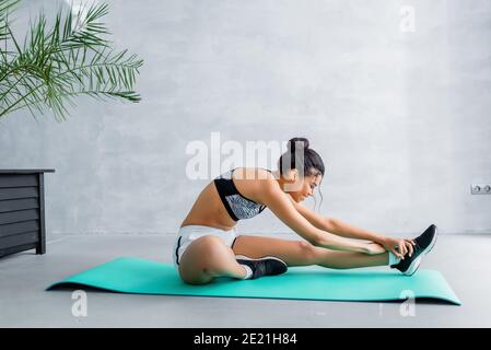 Lächelnde afroamerikanische Sportlerin macht Stretching-Übung auf Fitness-Matte Zu Hause Stockfoto