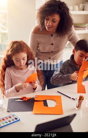 Zwei Kinder Zu Hause Mit Mutter, Die Spaß Macht Handwerk Gemeinsam Stockfoto