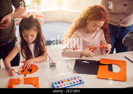 Zwei Mädchen Zu Hause Mit Eltern Mit Spaß Machen Handwerk Gemeinsam Stockfoto