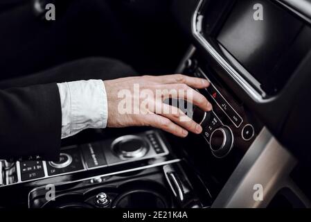 Nahaufnahme der männlichen Hand mit Audio-Radio-Stereo auf dem Auto-Panel. Transport- und Fahrzeugkonzept Stockfoto