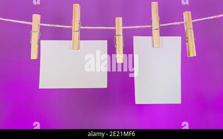 Closeup von leeren Noten hängen an einem Seil mit Wäscheklammern Isoliert auf einem violetten Hintergrund Stockfoto