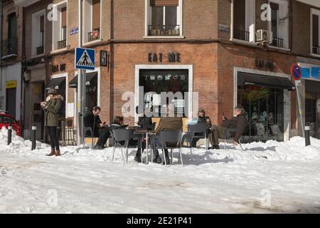 Madrid, Spanien - 10. Januar 2021: Eine Gruppe von Menschen genießen die Sonne und ein Bier in einer offenen Bar, im Retiro-Viertel, nach dem Sturm, an einem verschneiten Tag. Stockfoto