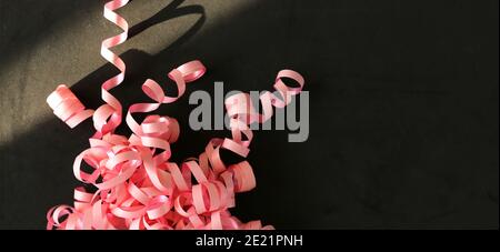 Rosa Serpentine Streamer auf schwarzem Hintergrund Party Accessoire Stockfoto