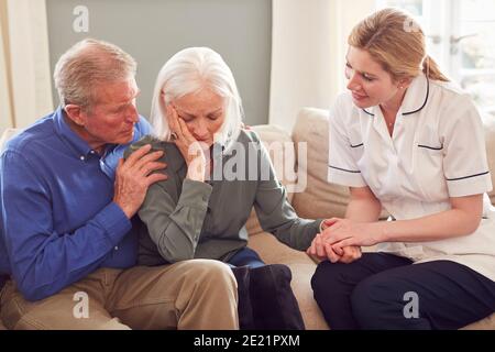 Weibliche Arzt Geben Schlechte Nachrichten Zu Älteren Paar Während Zu Hause Gesundheitsbesuch Stockfoto