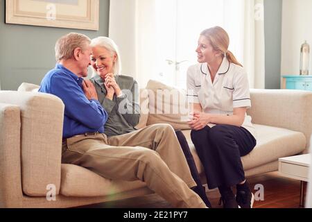 Weibliche Doctor Gute Nachrichten Zu Älteren Paar Während Zu Hause Geben Gesundheitsbesuch Stockfoto