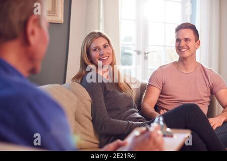 Männlicher Sozialarbeiter Mit Clipboard Besuch Junges Paar Zu Hause Stockfoto