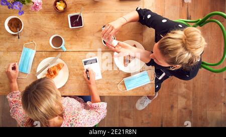 Zwei Freundinnen Im Coffee Shop Verwenden Hand Sanitizer Und Füllen Sie Das Test- Und Trace-Formular In Pandemie Aus Stockfoto