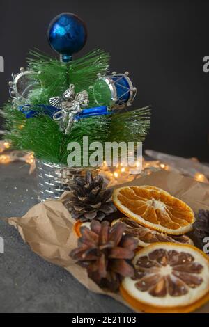 Weihnachtsbaum auf dunklem Tisch mit getrockneten Orangen und Tannenzapfen. Neujahrskarte, selektiver Fokus. Stockfoto