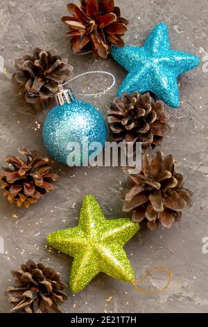 Ball und Sterne für Weihnachtsbaum auf dunklem Beton Hintergrund. Neujahrskarte mit Tannenzapfen. Selektiver Fokus, Nahaufnahme. Stockfoto