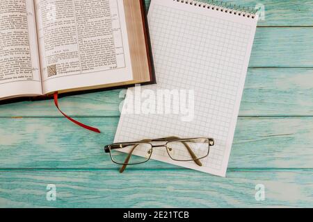 07. JANUAR 21 New York US 2021: Schreibtisch öffnet die Heilige Bibel Nahaufnahme der Gebetszeit in Brillen auf Notizblock Stockfoto