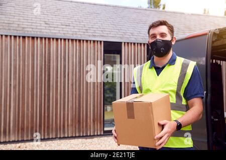 Porträt Der Lieferung Fahrer Trägt Maske Holding Paket Außerhalb Haus Stockfoto