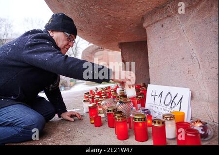 Berlin, Deutschland. Januar 2021. Initiator Christian Y. Schmidt stellt eine Kerze am Stierbrunnen im Prenzlauer Berg auf. Unter dem Brunnen im Park am Arnswalder Platz stehen Grablichter und Notizen mit Nummern über die Corona-Toten und weisen auf die Ernsthaftigkeit der Situation hin. Quelle: Annette Riedl/dpa/Alamy Live News Stockfoto