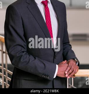 Gut aussehende unkenntlich Mann trägt einen schwarzen Anzug und rote Krawatte, und posiert Stockfoto