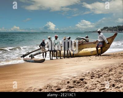 TANGALA, SRI LANKA - 15. März 2019: Asiatische Fischer schieben Holzboot auf dem Meer. Stockfoto