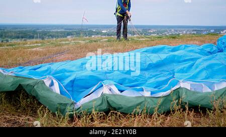 Nahaufnahme des Fallschirmflügels, der auf Gras auf dem Feld liegt Nach Fallschirmspringer Landung Stockfoto