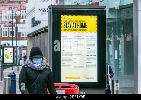 KINGSTON LONDON, GROSSBRITANNIEN 11. JANUAR 2021. Fußgänger gehen am ‘'Stay Home, Save Lives' Covid-19 Werbeplakat der Regierung in Kingston, Surrey, vorbei. Die Regierung hat bestätigt, dass Fälle und Todesfälle durch die mutierte Variante des SARS-Cov-2-Virus weiterhin im ganzen Land zunehmen. Mehrere Massenimpfzentren in England haben diese Woche für die Öffentlichkeit geöffnet, und die Regierung will bis Mitte Februar 15 Millionen Menschen impfen. Kredit: amer ghazzal/Alamy Live Nachrichten Stockfoto