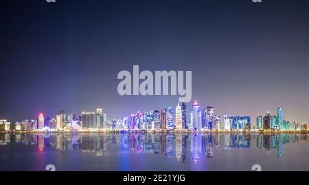 (Selektiver Fokus) atemberaubende Panoramaaussicht auf die Doha Skyline, die in der Abenddämmerung während der Covid-19 Pandemie beleuchtet wird. Stockfoto