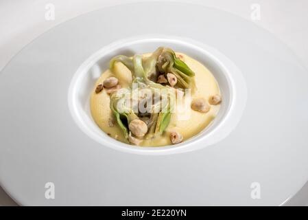 Artischocken auf Fontina Fondue mit Haselnüssen 'Tonda Gentile di Langa', Piemont, Italien in weißer Schale Stockfoto